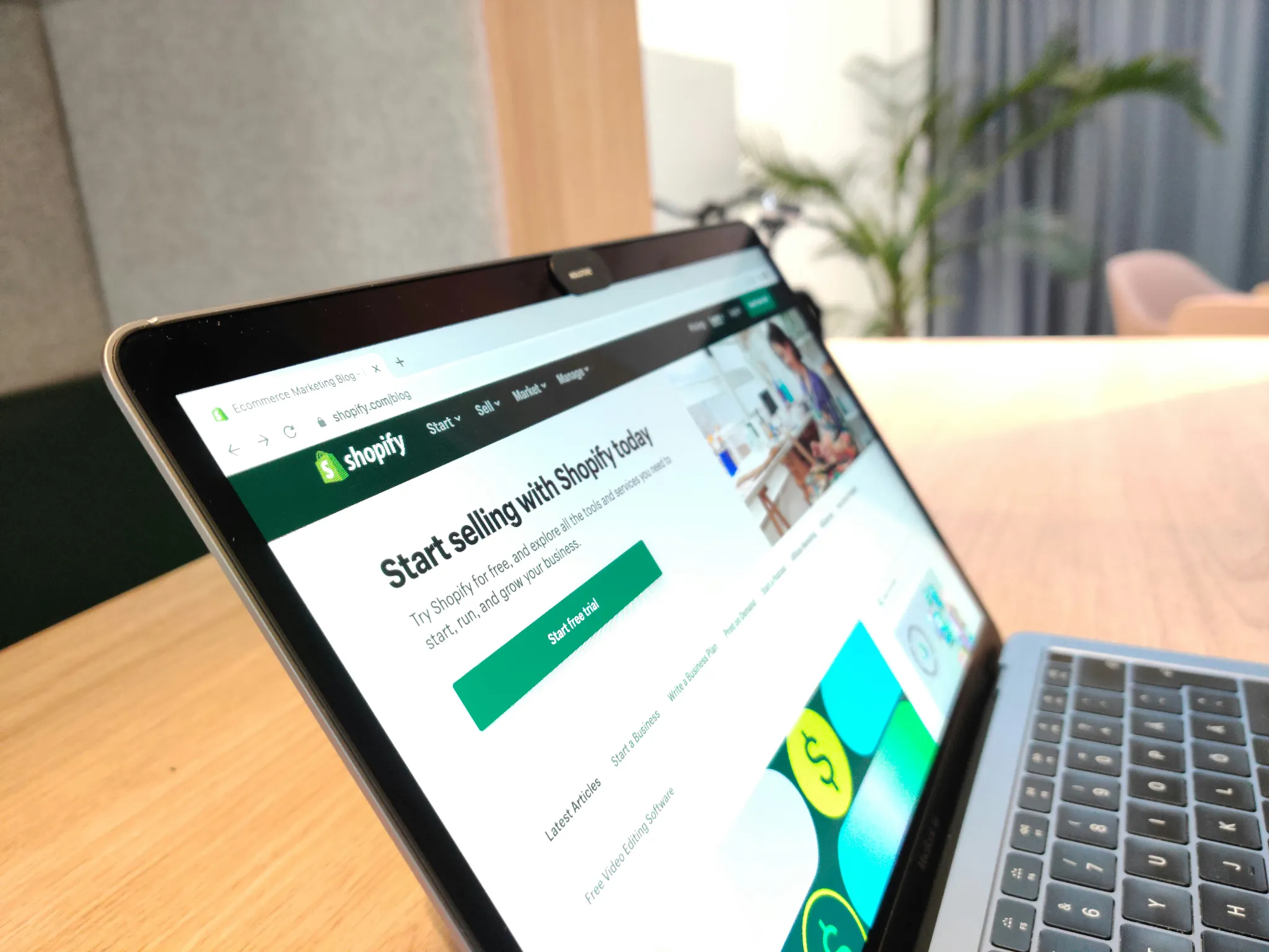 Laptop displaying the Shopify website on a desk in a bright office.